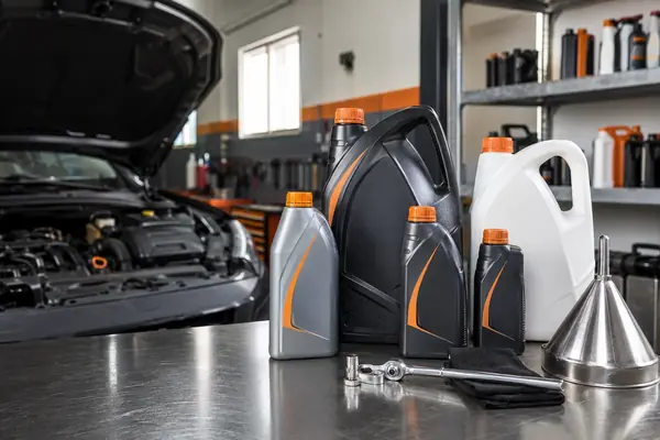 Bidons d'huile moteur et fluides techniques sur l'établi de l'atelier Nabaya